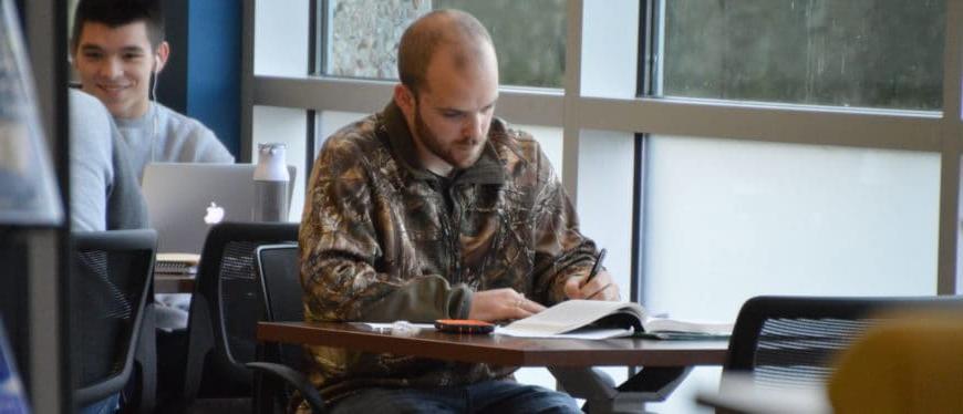 Student studying at a table by windows