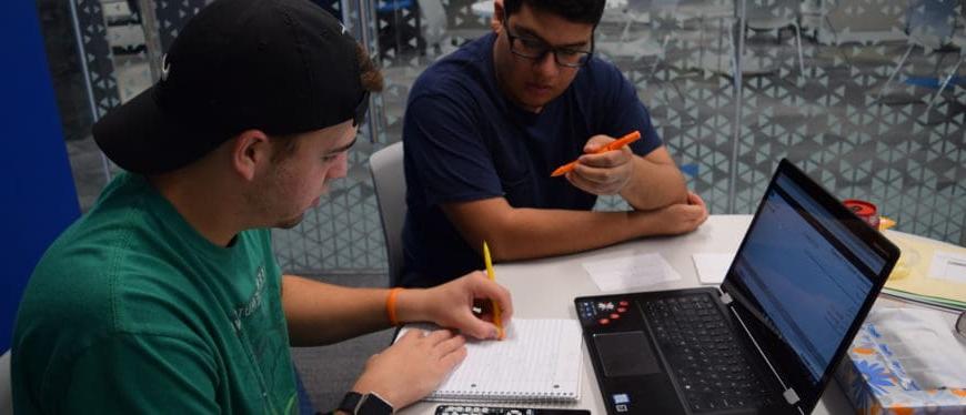 two males interacting while sitting at a desk at tutoring center